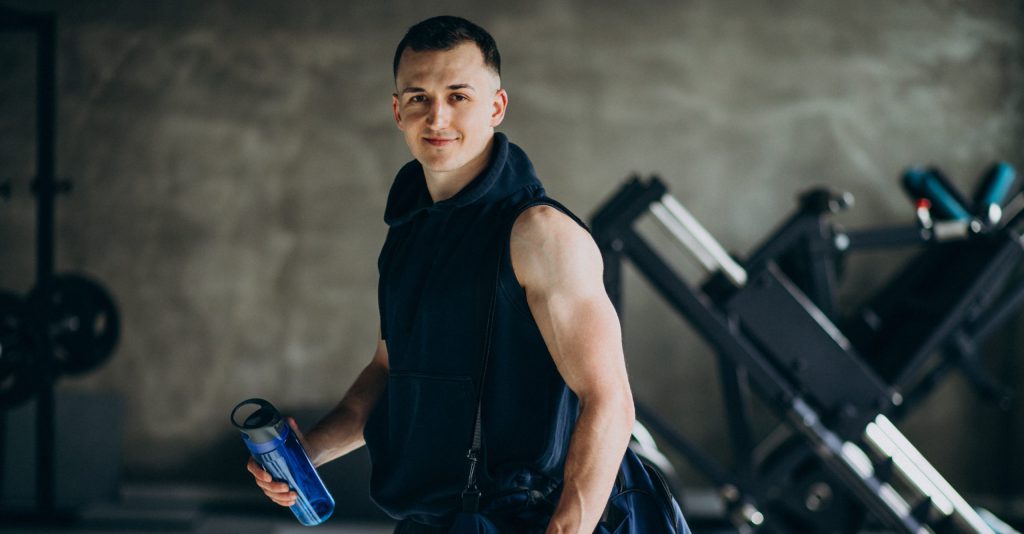 sportowiec z torbą treningową i shakerem, suplementy diety na siłownię, przygotowanie do treningu