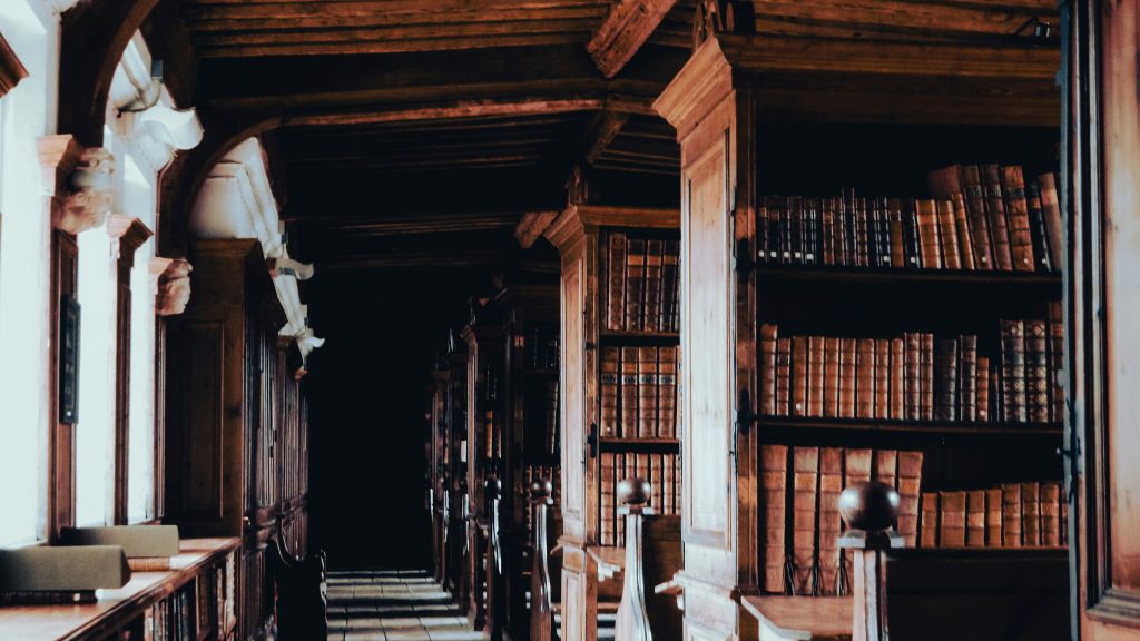 Wnętrze starej biblioteki z wysokimi, drewnianymi regałami wypełnionymi książkami