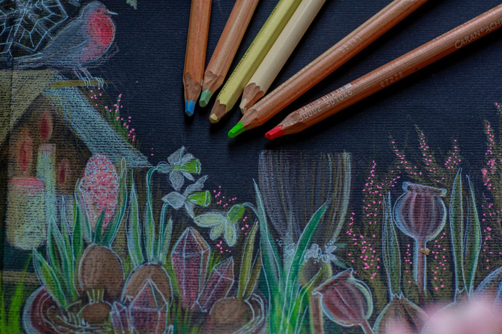 Na zdjęciu widać czarną kartkę papieru z kolorowym rysunkiem wykonanym kredkami