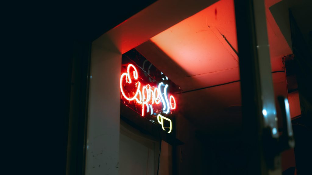 Na zdjęciu widać neonowy napis „Espresso” świecący intensywnym czerwono-białym światłem