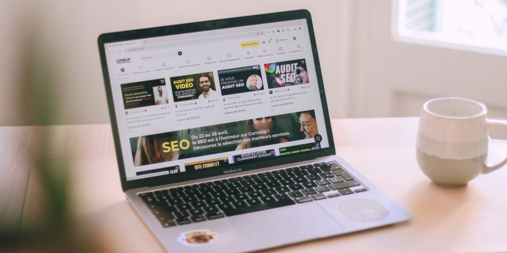 Na zdjęciu widać otwarty laptop stojący na drewnianym biurku